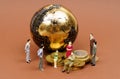 Miniature business people stand near a globe and coins. Royalty Free Stock Photo