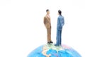 Miniature businessman on the globe on white background