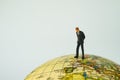 Miniature businessman leader standing and looking on Europe map