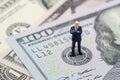 Miniature businessman leader standing and thinking on US Federal Reserve emblem on US dollars banknote as FED consider interest