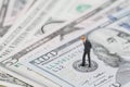 Miniature businessman leader standing and thinking on US Federal Reserve emblem on five dollars banknote as FED consider interest