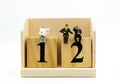 Miniature businessman sitting on number wooden block. Image use for business concept