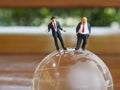 Miniature businessman stand on globe of glass with wooden background. Business and idea concept. Royalty Free Stock Photo