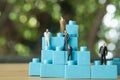 Miniature businessman standing on blue block