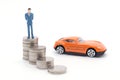 Miniature businessman standing on coins and the car behind. saving and loan concept. Royalty Free Stock Photo