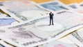 Miniature businessman standing on Japanese banknotes