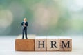 Miniature businessman standing on wooden block word HRM Human resource management : HRM Royalty Free Stock Photo