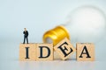 Miniature businessman on Wooden cubes with words `idea` on light bulb background. concept of ideas to change perspectives,