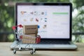 Miniature cardboard boxes in shopping cart with laptop computer Royalty Free Stock Photo