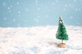 Miniature Christmas Tree with snowfall. Copy space for text. Holiday and celebration concept.