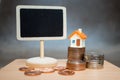 Miniature colorful house on stack coins with blank blackboard us