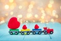 Miniature colorful train carrying a red hearts onwooden turquoise background with shine bokeh