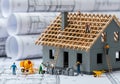 Miniature construction workers building a house model on blueprints Royalty Free Stock Photo