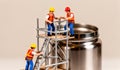 Miniature construction workers building a scaffold beside a sleek silver container Royalty Free Stock Photo
