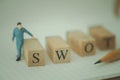 Miniature workers moving wood word SWOT place on paper Royalty Free Stock Photo
