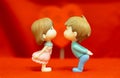 The Miniature Couple dolls Boy and Girl Romantic Kiss on Red Heart Background for valentine`s Day Concept