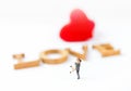 Miniature couple over blurred love font and red heart background