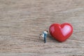 Miniature couple with red heart love symbol on wooden table, hus