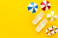 Miniature deckchairs, sun umbrellas, lifebuoys on the beach, Yellow background, copy space, Vacation and recreation concept