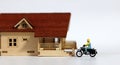 A miniature delivery man riding a motorcycle in front of the door of a miniature house. Royalty Free Stock Photo