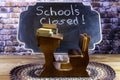 Miniature desk and school closed written on chalk board