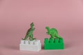 Miniature dinosaurs standing on two blocks of children`s constructor. Two Small green miniatures of predatory dinosaurs standing