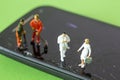 Miniature Doctor and Nurse standing on a broken screen of a cellphone