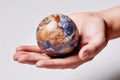 Miniature Earth in Hand: Close-up of Intricate Planet Surface on White Background