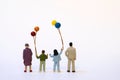 Miniature family with children and colorful balloons - white background, copy space Royalty Free Stock Photo