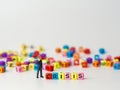 Miniature figure businessman in dark blue suit standing backside of colorful of CRISIS alphabet and thinking of the crisis will co Royalty Free Stock Photo