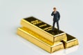 Miniature figure businessman standing and thinking on shiny gold Royalty Free Stock Photo