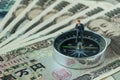 miniature figure businessman thinking standing on compass on pile of japanese yen banknotes as financial leader direction concept Royalty Free Stock Photo