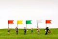 Miniature figure of businessmans and multi-color flags at the go