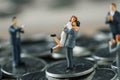 Miniature figure couple people standing on top stack of coins an