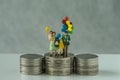 Miniature figure family with balloon standing on stack of coins Royalty Free Stock Photo