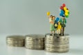Miniature figure family holding balloon standing on stack of coins as financial business or happy concept Royalty Free Stock Photo
