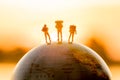 Miniature figure people backpack standing on globe with sunset