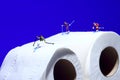 Miniature figure people skiing on toilet roll tissue
