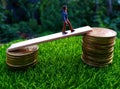 Miniature figure young bussinesman keep trying to get higher income walking at stack of coin at fresh green grass in the morning Royalty Free Stock Photo