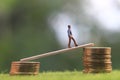 Miniature figure young bussinesman keep trying to get higher income walking at stack of coin at fresh green grass in the morning Royalty Free Stock Photo