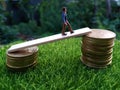 Miniature figure young bussinesman keep trying to get higher income walking at stack of coin at fresh green grass in the morning Royalty Free Stock Photo