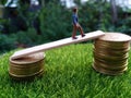 Miniature figure young bussinesman keep trying to get higher income walking at stack of coin at fresh green grass in the morning Royalty Free Stock Photo