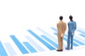 Miniature figures businessmen standing on a graph chart financial