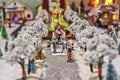 Miniature figures of man in tuxedo and lady in dress, coachman and carriage in miniature winter park