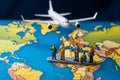 Miniature figures, representing male and female travelers, stand near a world map and airplane Royalty Free Stock Photo