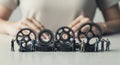 Miniature figures working with gears against blurred background of hands on a white surface Royalty Free Stock Photo