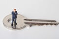 Miniature figurine of a business man on a giant key Royalty Free Stock Photo