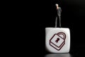 Miniature figurine of a businessman on the top of the symbol of a padlock