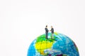 Miniature figurine character as businessmen standing on world globe toy and shaking hands together. Royalty Free Stock Photo