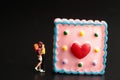 Miniature figurine of a a couple of lovers kissing with a giant dessert